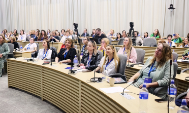 Participants in the conference sitting at desks in rows in a conference room