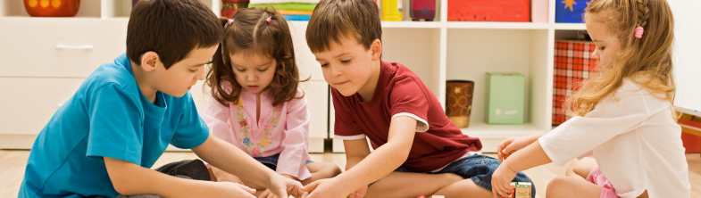 Four children play with building blocks that have numbers and letters on them